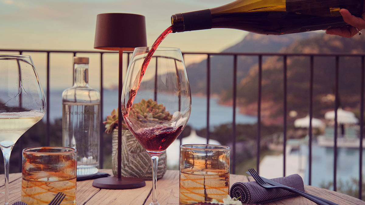 Wine being poured with the a sea and mountain backdrop